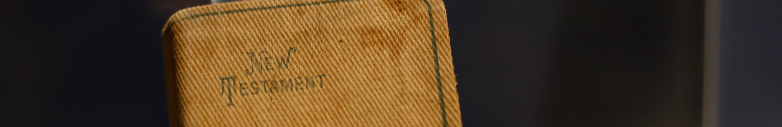 Cropped close-up of a small canvas-bound book with 'New Testament' printed on the cover.